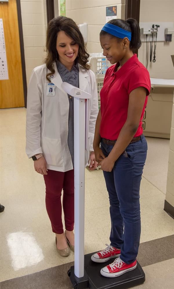 West TN Healthcare nurse works helps student weigh themself.  